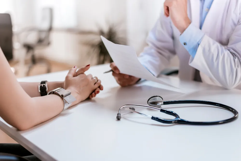 Profissional em consulta médica apresentando documentos ao paciente, representando exame de retorno ao trabalho obrigatório após afastamento.