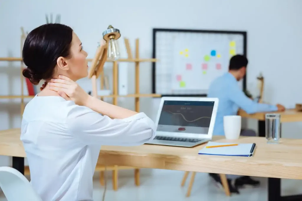 Mulher segurando o pescoço com expressão de dor, representando a importância da análise ergonômica do trabalho (AET)