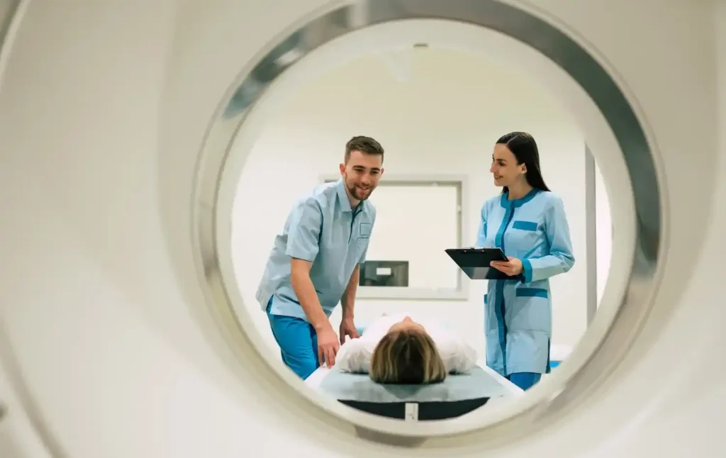 Dois médicos realizando exame de tomografia computadorizada em um paciente