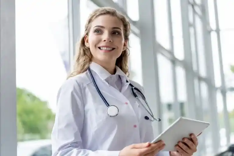 Profissional de saúde sorrindo com tablet nas mãos, representando o uso da telemedicina no SUS