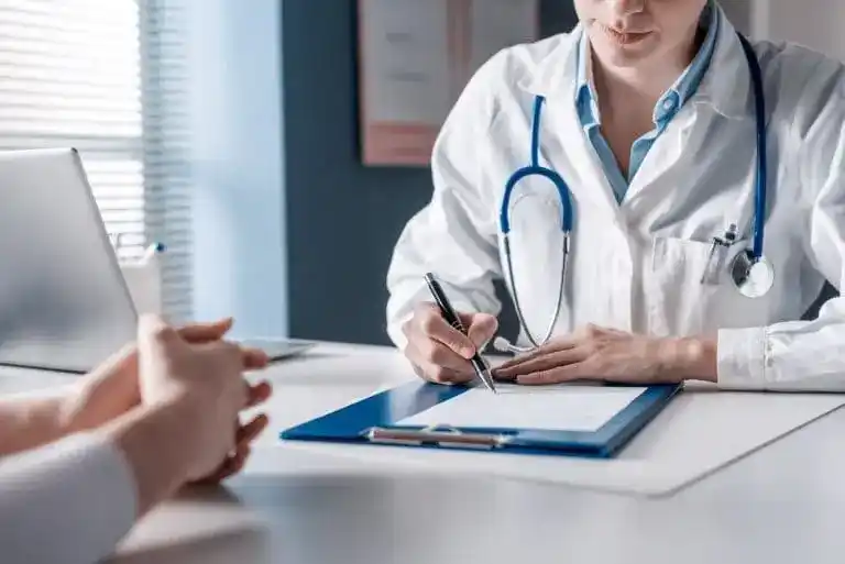 Médico do trabalho preenchendo o ASO (Atestado de Saúde Ocupacional) durante consulta ocupacional.