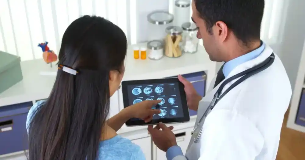 Médico mostrando imagens de exames para paciente, ilustrando o uso do PACS para visualização e comunicação de imagens médicas