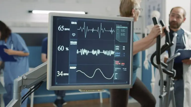 Monitor hospitalar mostrando gráfico de eletrocardiograma e batimentos cardíacos normais durante avaliação médica