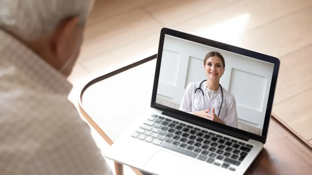 Paciente realiza teleconsulta com médica pelo computador, aproveitando atendimento online em saúde.
