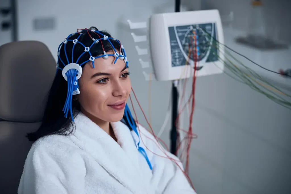 Paciente realizando eletroencefalograma com mapeamento cerebral, utilizando touca com eletrodos para análise da atividade cerebral.