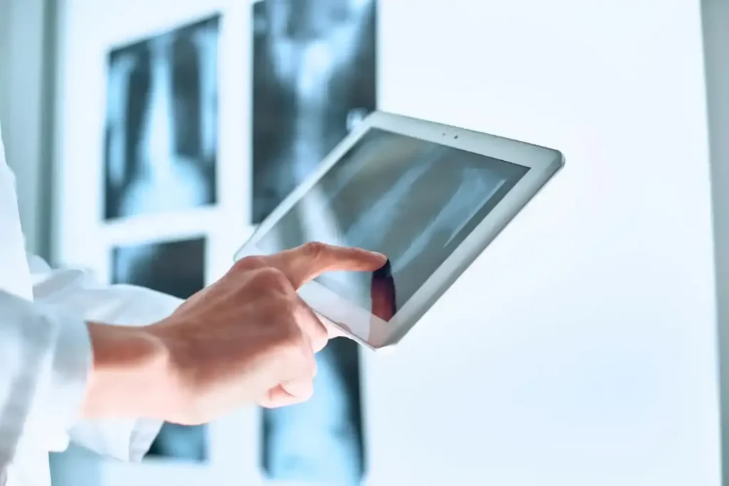 Profissional de saúde analisando exame digital em tablet durante procedimento de telerradiologia